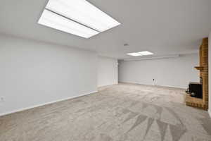 Basement featuring light colored carpet and a wood stove