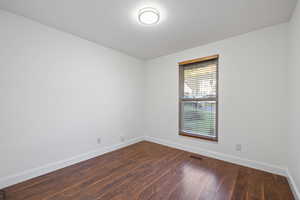 Unfurnished room with dark wood-style flooring and baseboards