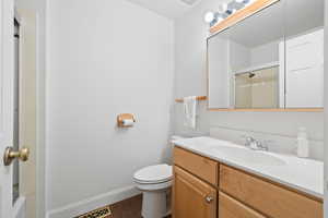 Full bathroom with vanity, dark wood-style flooring, and combined bath / shower with glass door