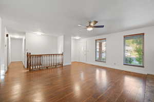 Unfurnished room with wood finished floors, ceiling fan, and a textured ceiling