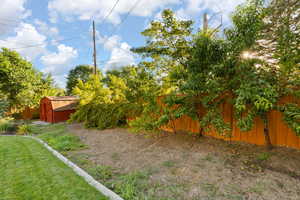 Fenced backyard featuring a shed