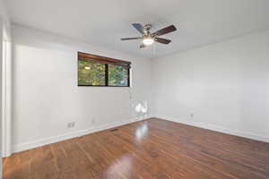 Empty room with dark wood-style flooring and a ceiling fan