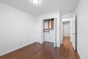 Unfurnished bedroom featuring dark wood-style floors and a closet