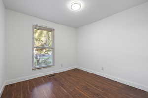 Spare room with baseboards and dark wood finished floors