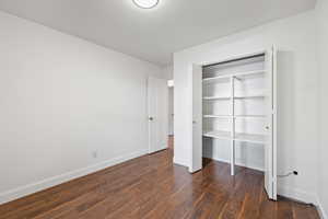Unfurnished bedroom featuring dark wood-type flooring and a closet