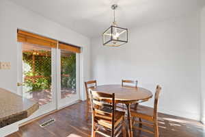Dining area with dark wood-type flooring and a chandelier