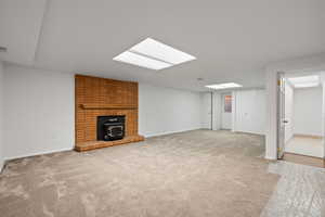 Finished basement with a wood stove and light colored carpet