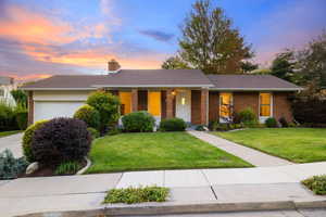 Ranch-style home with a porch, a garage, a front lawn, and brick siding