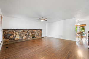 Unfurnished living room with dark wood-style flooring, a ceiling fan, a fireplace, and a textured ceiling