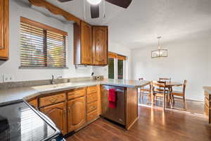 Kitchen with black range with electric stovetop, brown cabinetry, a peninsula, dark wood-style flooring, and dishwasher
