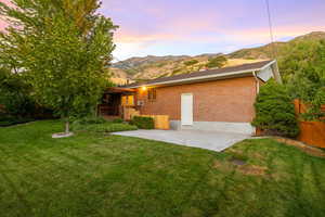 Back of house with a patio, a mountain view, brick siding, and a chimney