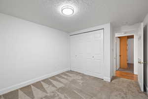 Unfurnished bedroom with carpet, a closet, and a textured ceiling