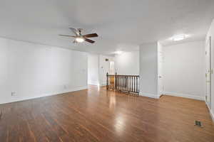 Unfurnished room with dark wood-type flooring, a textured ceiling, and a ceiling fan
