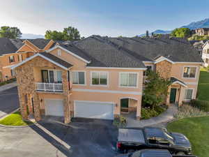 Traditional-style home featuring stone siding, a balcony, stucco siding, and an attached garage