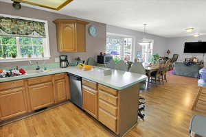 Kitchen featuring open floor plan, a peninsula, light countertops, light wood-type flooring, and stainless steel appliances