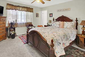 Bedroom with light colored carpet and a ceiling fan