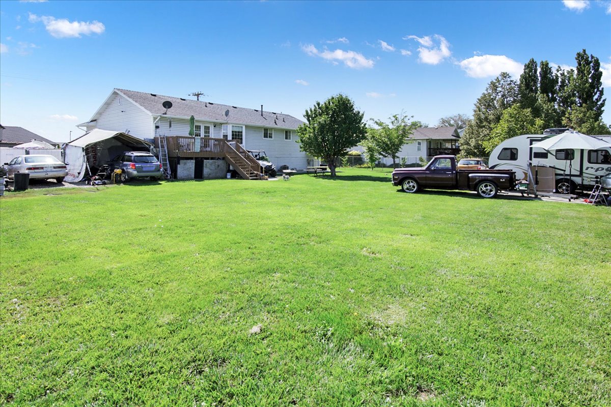 View of grassy yard with stairway and a wooden deck