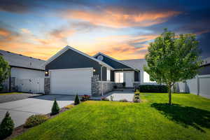 View of front of home featuring concrete driveway, stucco siding, a garage, a gate, and stone siding