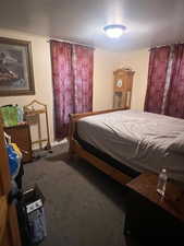 Carpeted bedroom featuring a textured ceiling and baseboards