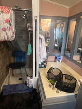 Full bath with a stall shower, vanity, and ornamental molding