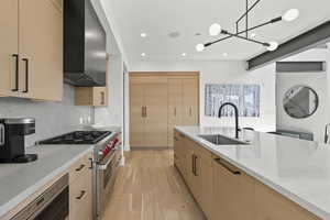 Kitchen featuring stainless steel appliances, light stone countertops, light wood finished floors, light brown cabinetry, and modern cabinets