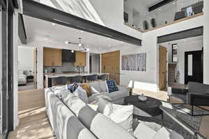 Living area featuring light wood-type flooring, recessed lighting, a towering ceiling, and stairway