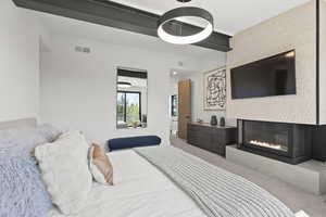 Carpeted bedroom with a glass covered fireplace