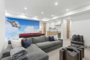Living area with light carpet, bar with sink, recessed lighting, billiards, and beverage cooler
