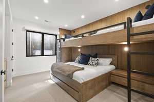 Bedroom with wood walls, light carpet, and recessed lighting