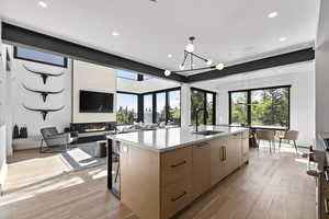 Kitchen featuring light wood-style flooring, a center island with sink, recessed lighting, modern cabinets, and stainless steel stove