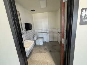 Bathroom with tile walls and a wainscoted wall