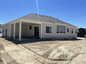 Back of house featuring a patio area and roof with shingles