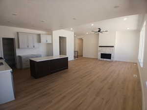 Kitchen with a kitchen island, dark wood-style floors, recessed lighting, a stone fireplace, and open floor plan
