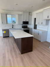 Kitchen featuring tasteful backsplash, appliances with stainless steel finishes, a center island, white cabinetry, and recessed lighting