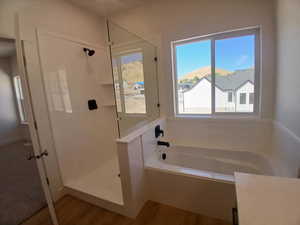 Bathroom featuring a shower stall, a garden tub, and wood finished floors