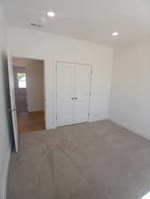 Unfurnished bedroom featuring recessed lighting, carpet floors, and a closet