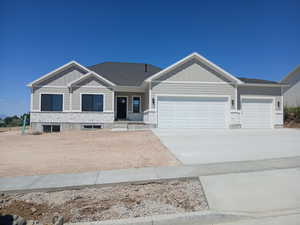 Craftsman-style home with a garage, driveway, stone siding, covered porch, and board and batten siding