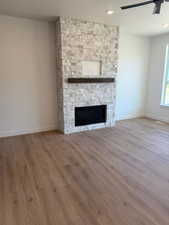Unfurnished living room with a stone fireplace, ceiling fan, light wood-style floors, and recessed lighting
