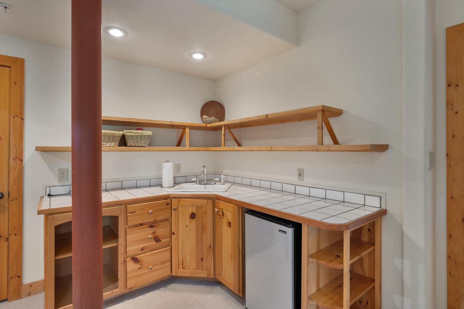 Kitchen featuring open shelves, tile countertops, stainless steel fridge, and recessed lighting