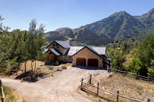 View of front facade with stone siding, dirt driveway, a garage, a metal roof, and a mountain view