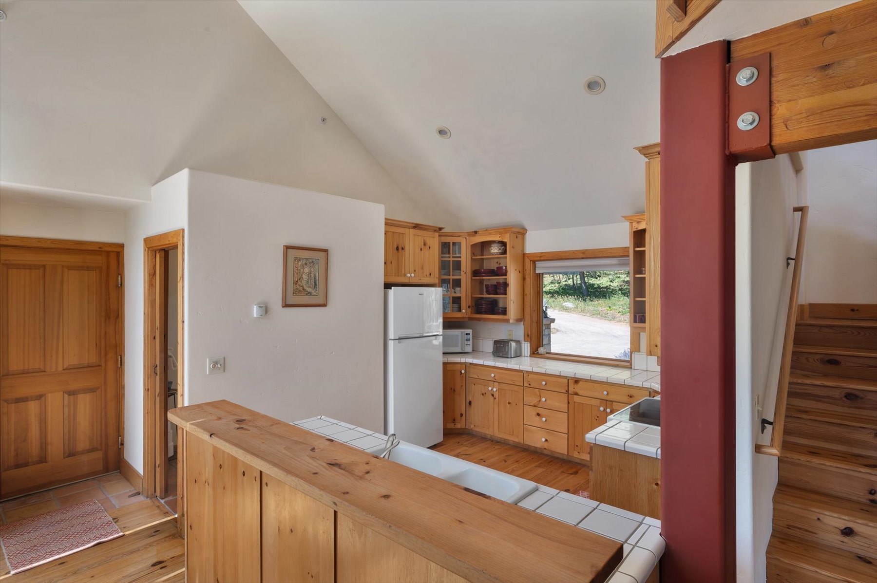 Kitchen with tile counters, white appliances, knotty pine floors, glass insert cabinets, and recessed lighting