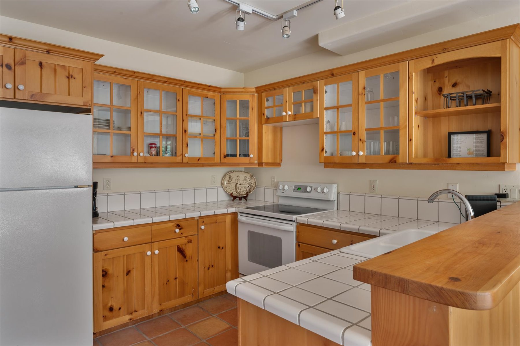 Kitchen featuring white appliances, luxury vinyl plank flooring, track lighting, and glass insert cabinets