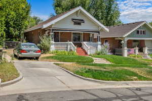 Bungalow-style home featuring covered porch, brick siding, a shingled roof, and stairway