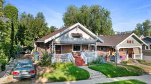 View of front of property featuring a porch, brick siding, and roof with shingles