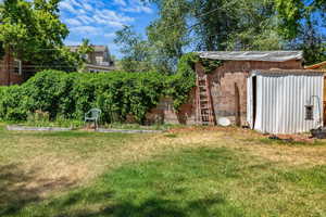 View of grassy yard with a storage unit