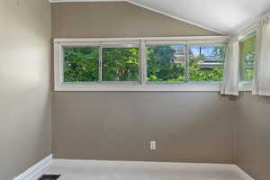 Carpeted spare room with baseboards and vaulted ceiling
