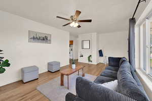 Living area with light wood-style floors, a textured ceiling, and a ceiling fan