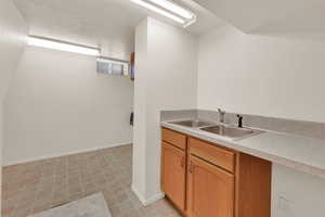 Kitchen featuring light countertops, brown cabinetry, a textured ceiling, and light tile patterned floors