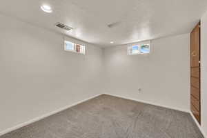 Below grade area featuring light carpet and a textured ceiling