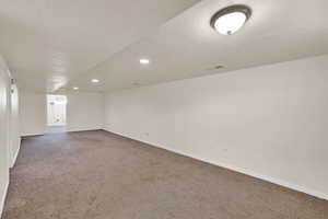 Finished basement with light colored carpet, a textured ceiling, and recessed lighting